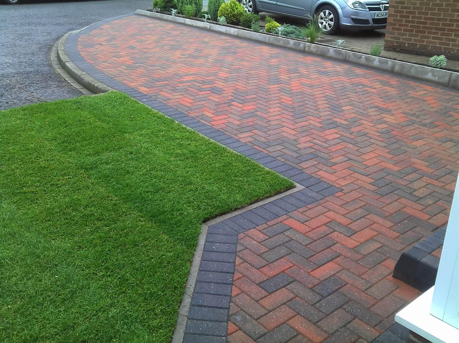 Red and charcoal herringbone block paving around a lawn